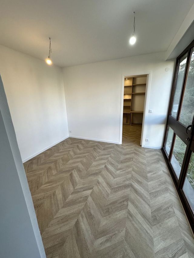 Pièce avec baies vitrées après aménagement : murs blancs et parquet posé à chevrons