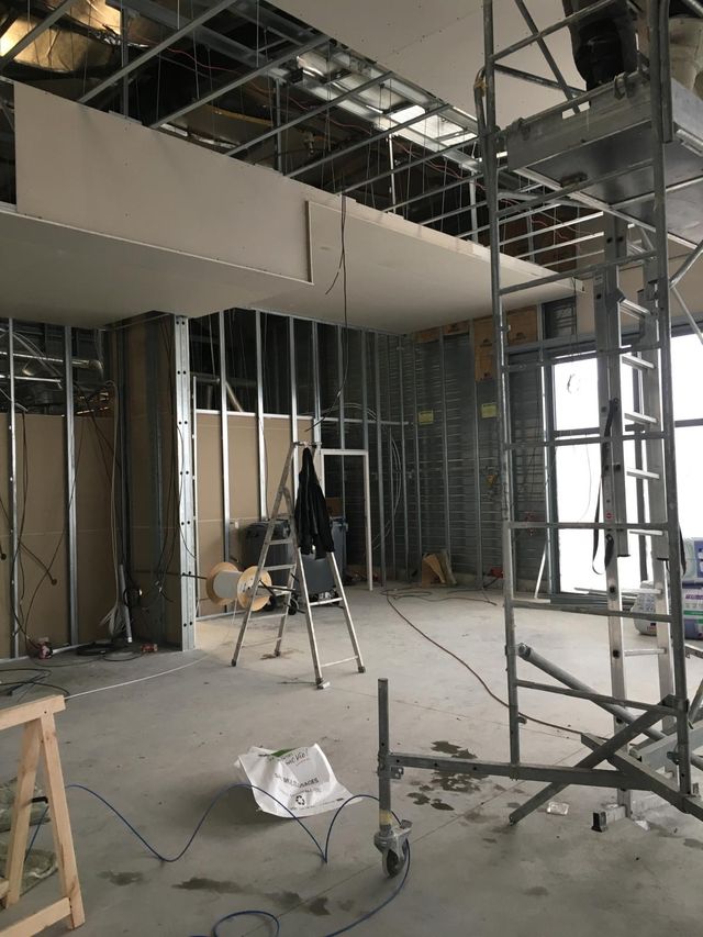 Restaurant pendant les travaux : ossatures métalliques, plaques de plâtre en cours de pose, faux plafond ouvert et échafaudage
